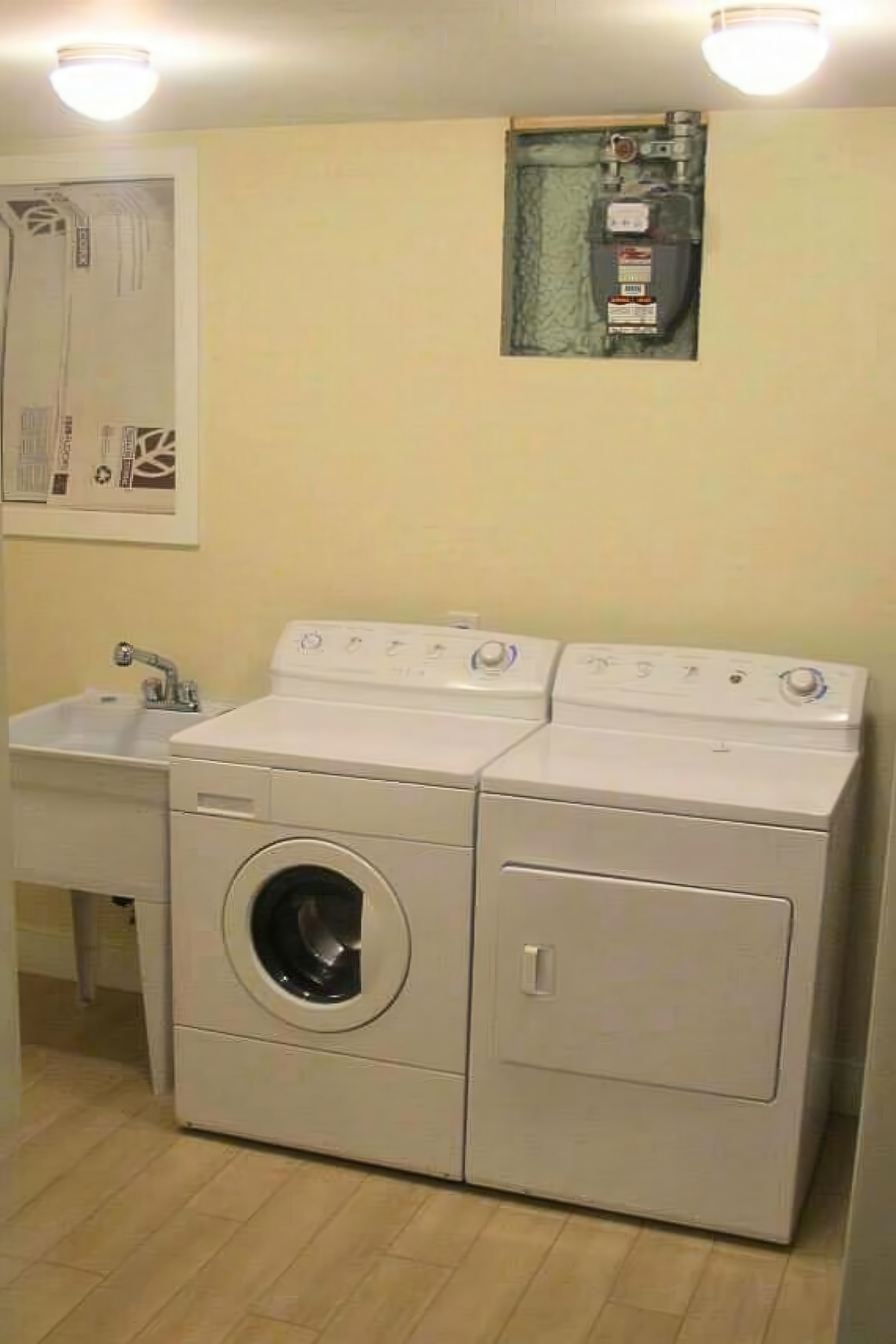 Completed laundry room with washer, dryer, and utility sink in Philadelphia rowhome
