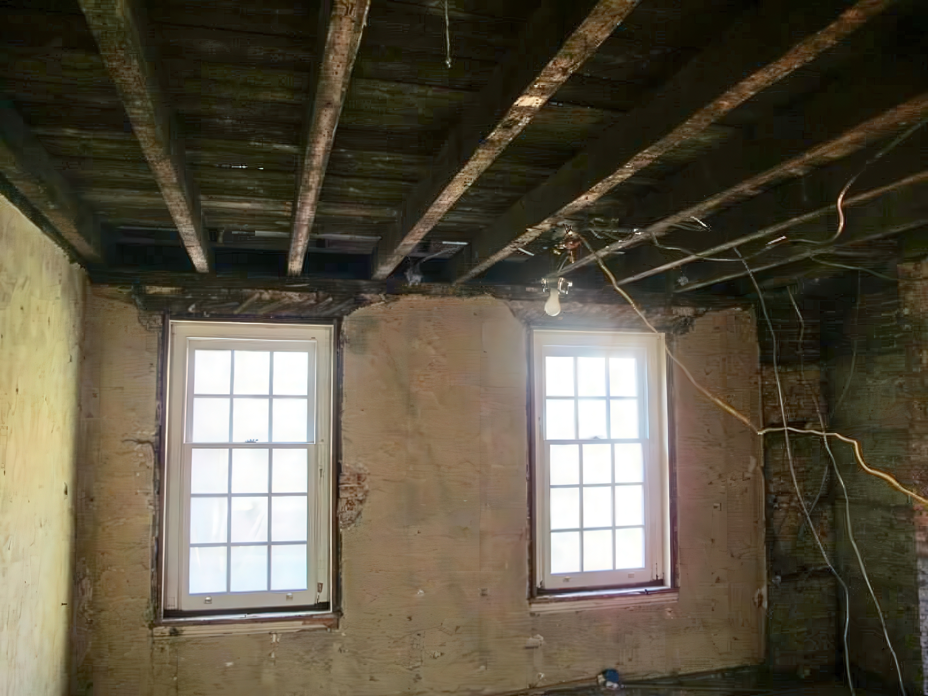 Room during demo with exposed joists and window openings