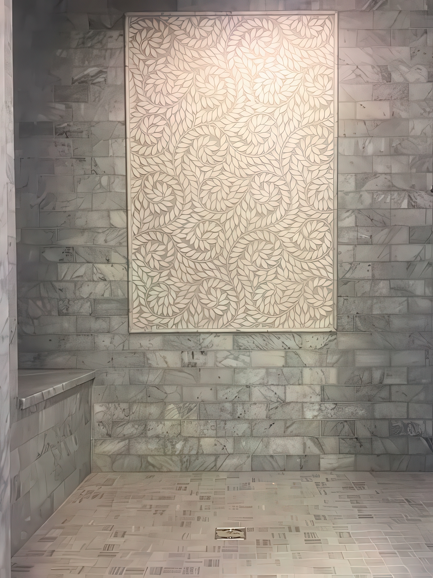 Large decorative leaf mosaic panel on marble subway tile shower wall