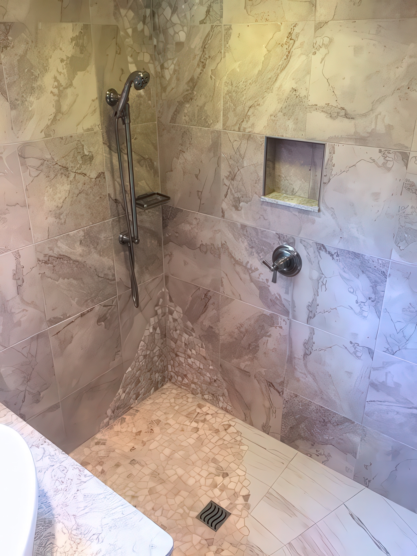 Walk-in shower with natural stone tile, hand shower bar, recessed niche, and pebble mosaic floor