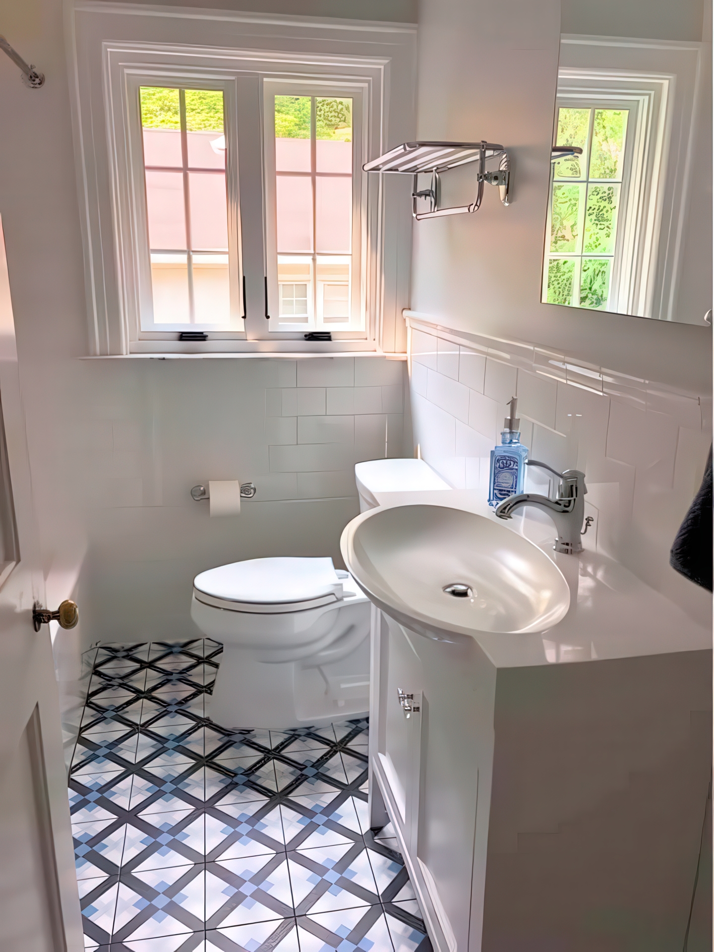Wide view of powder room with toilet, vanity, patterned floor tile, subway wainscoting, and double windows