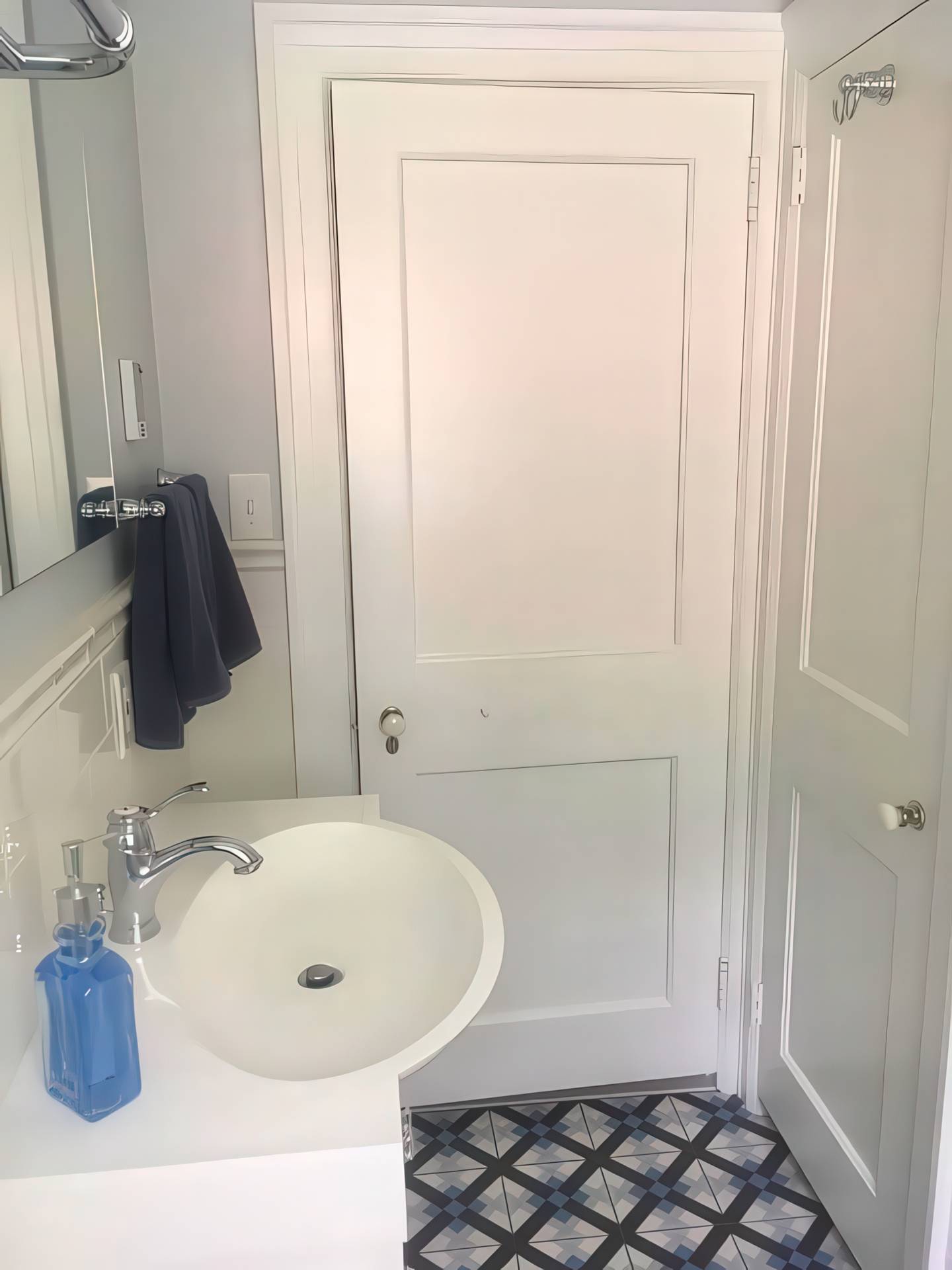 Vanity and door detail showing patterned floor tile and chrome fixtures