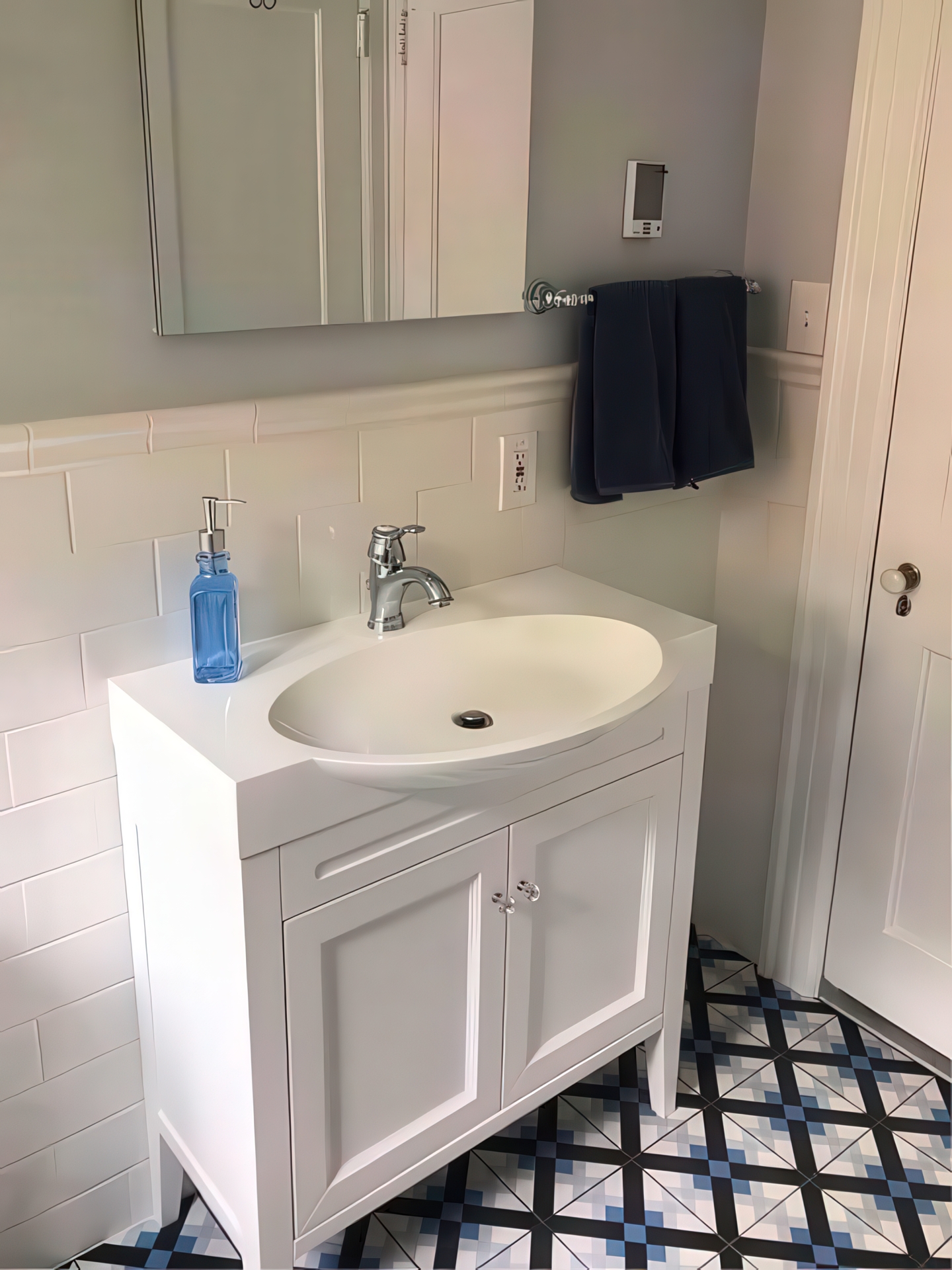 White vanity with chrome faucet and geometric blue and black patterned floor tile