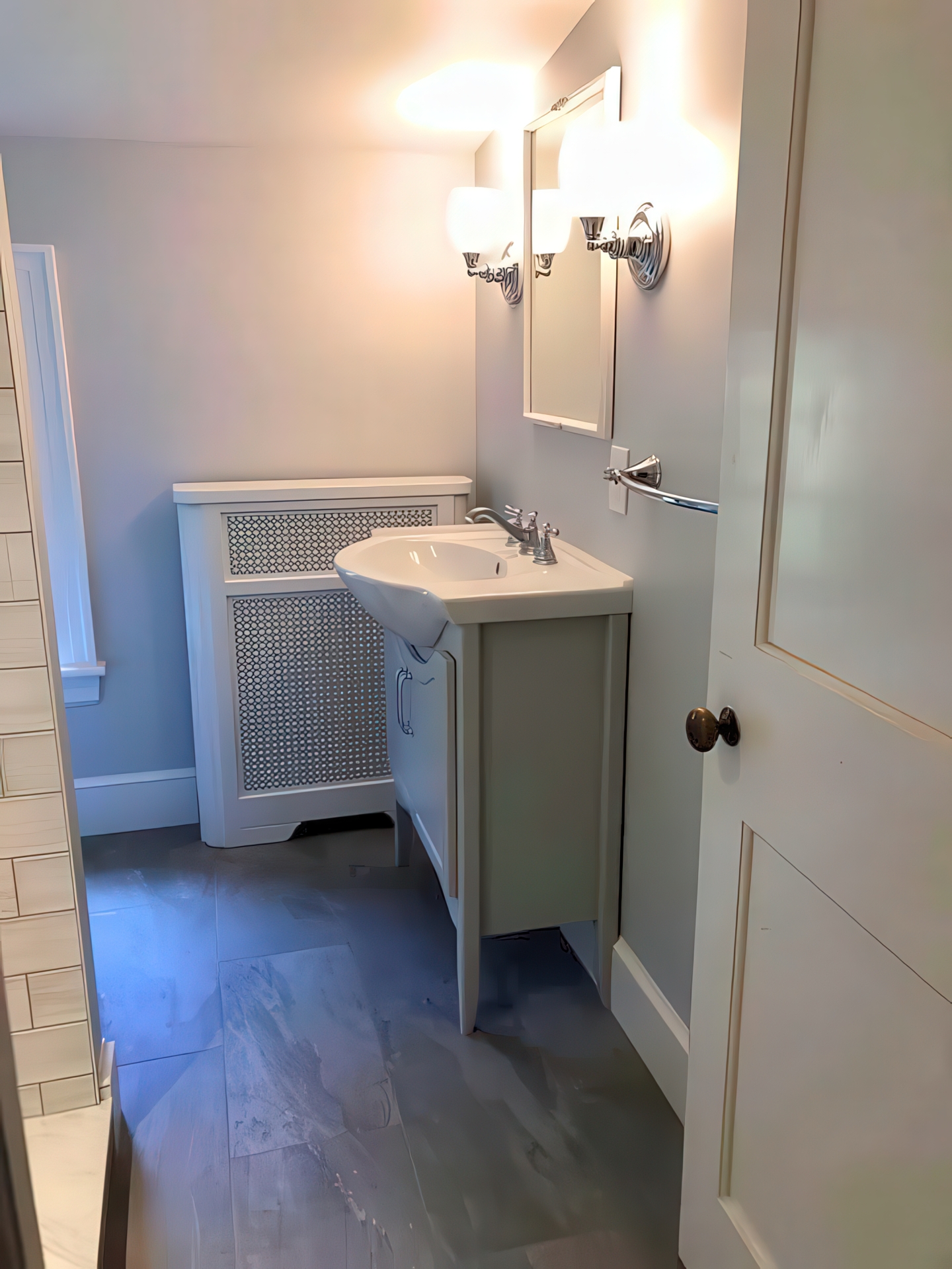 Larger bathroom vanity with decorative radiator cover, sconce lighting, and gray tile floor