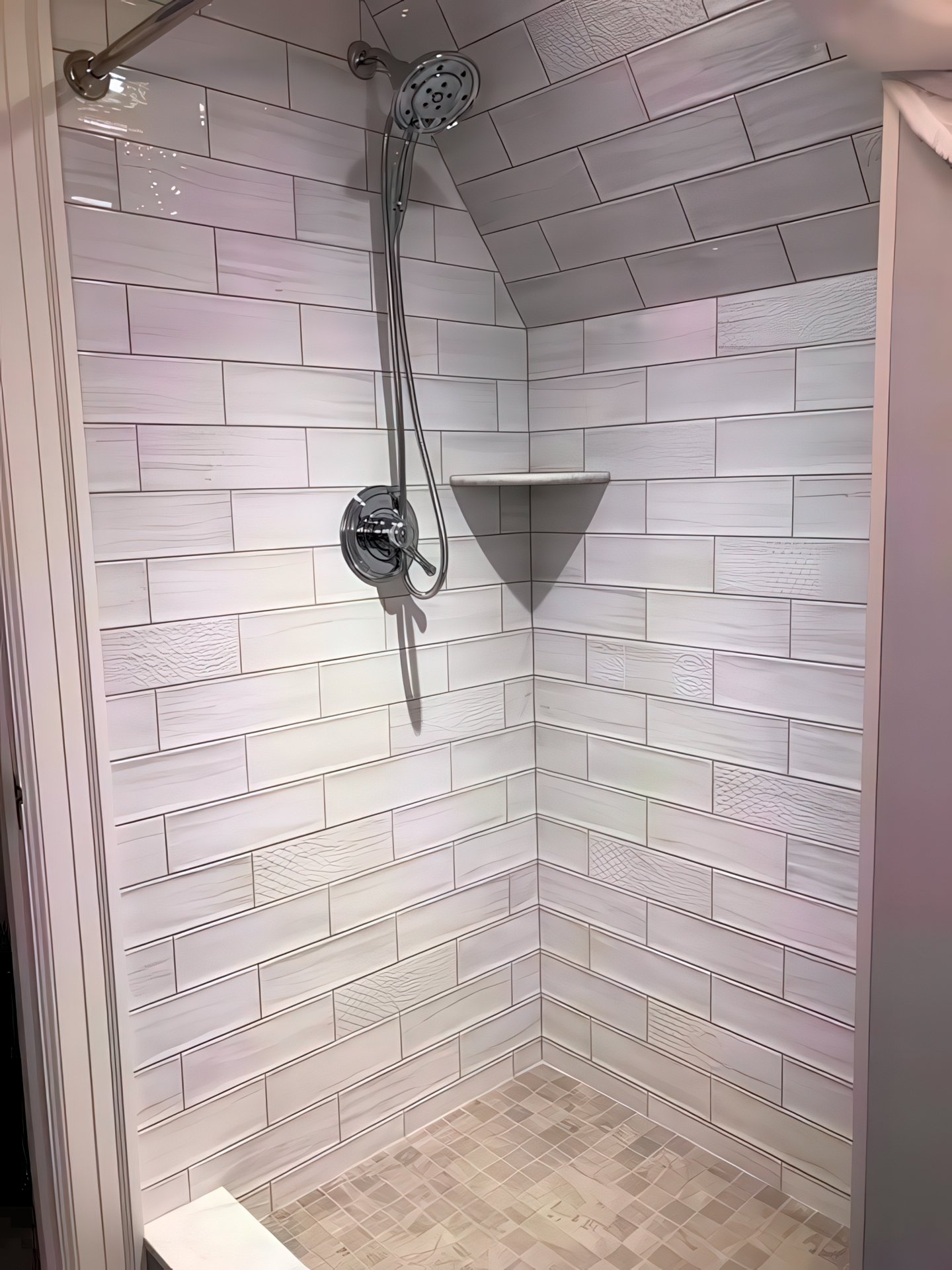 Walk-in shower with large gray and white marble-look tile and corner marble seat