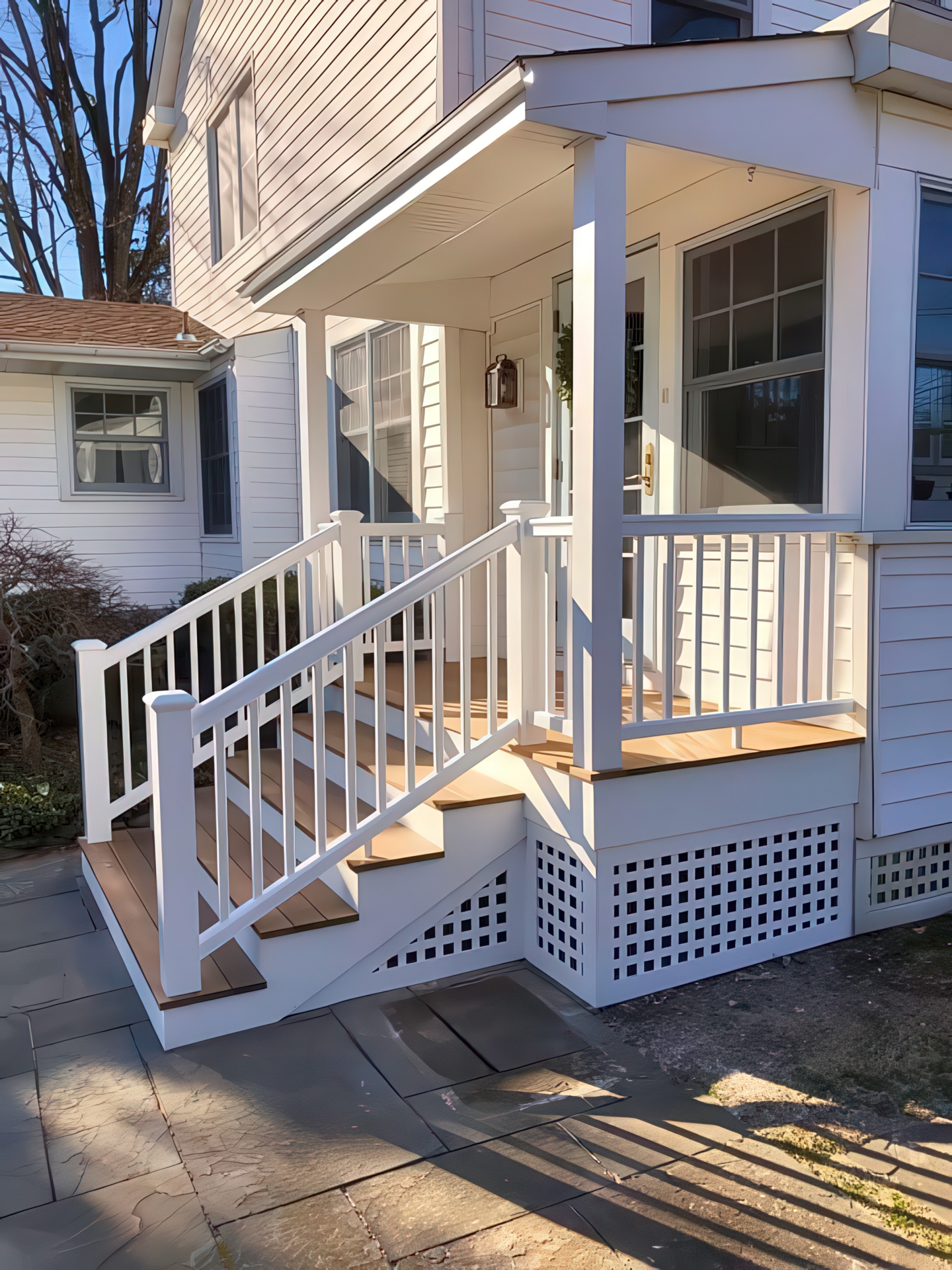 Side angle showing white PVC railings, composite steps, and lattice skirting