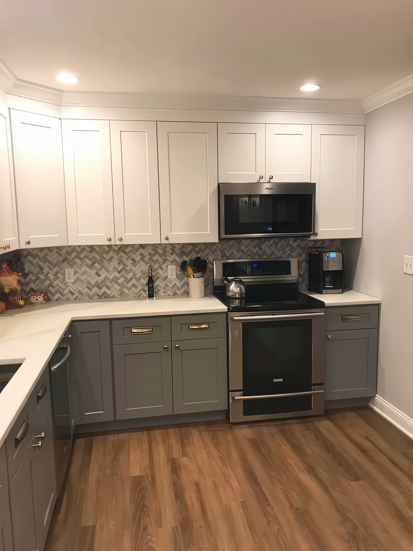 Range and microwave wall with gray lower cabinets, white upper cabinets, and herringbone backsplash