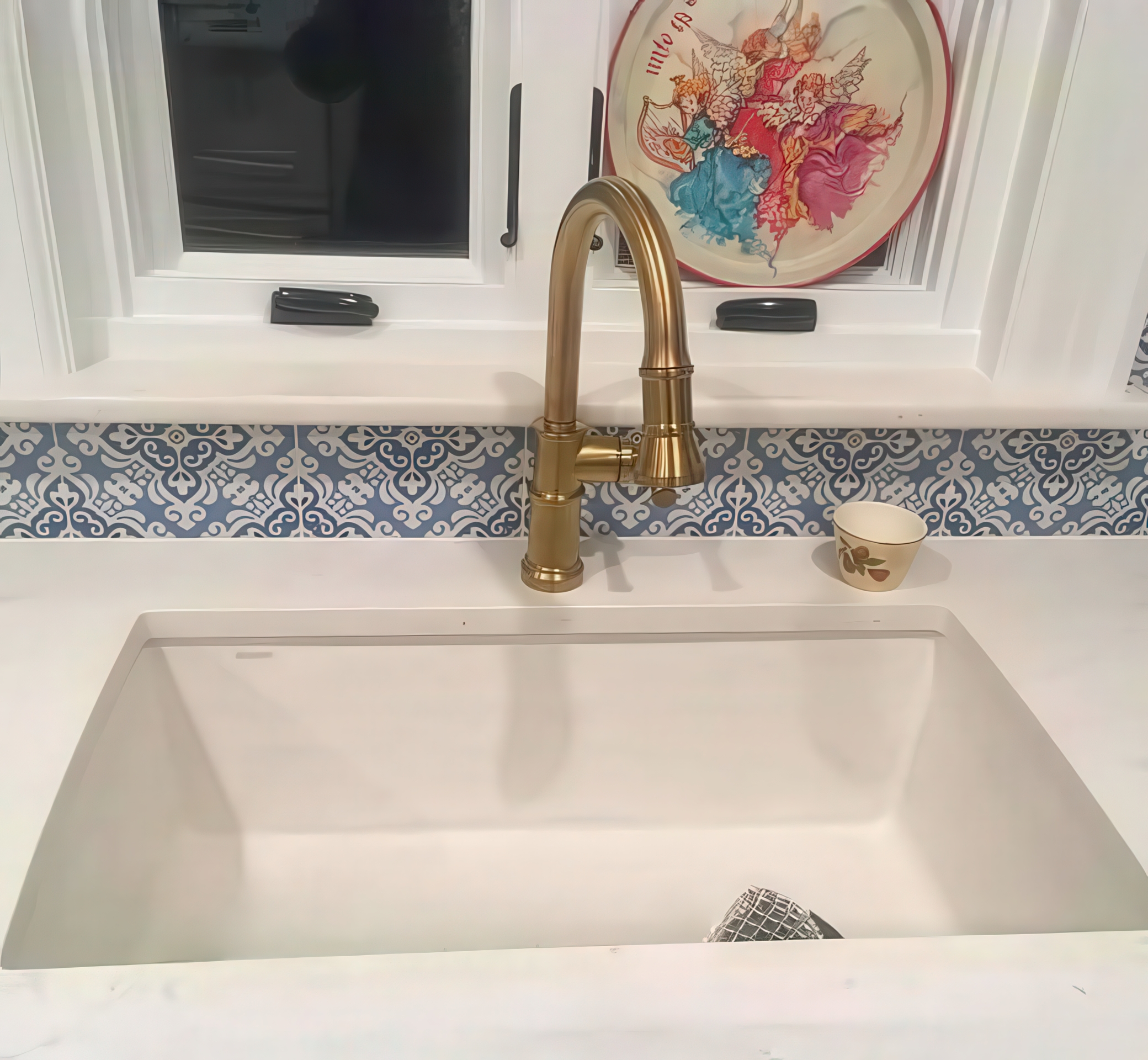 Undermount sink with brass faucet and blue patterned backsplash tile